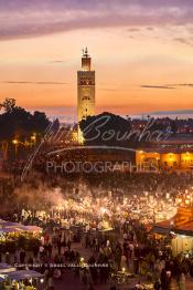 Image du Maroc Professionnelle de  Au coucher du soleil et même un peu avant la foule envahi la fameuse Place Jemaa El Fana qui se métamorphose en un gigantesque restaurant en plein air grâce aux nombreux stands et gargotes qui s'y installent sur ce lieu mythique au centre de la médina de Marrakech. Au fond le minaret de la Koutoubia, Samedi 26 Février 2005. (Photo / Abdeljalil Bounhar)

